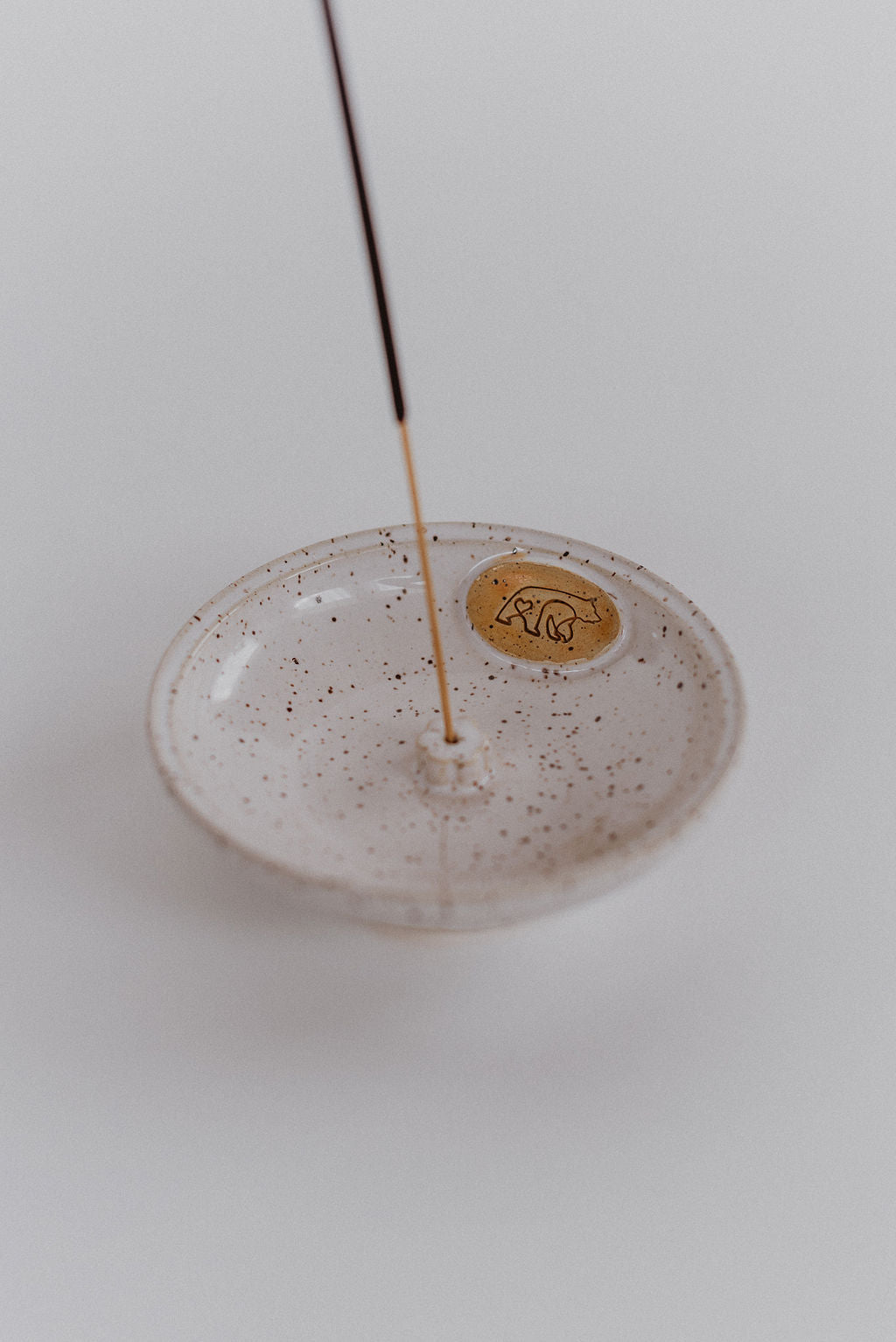 An incense stick holder with the wick and bear logo.