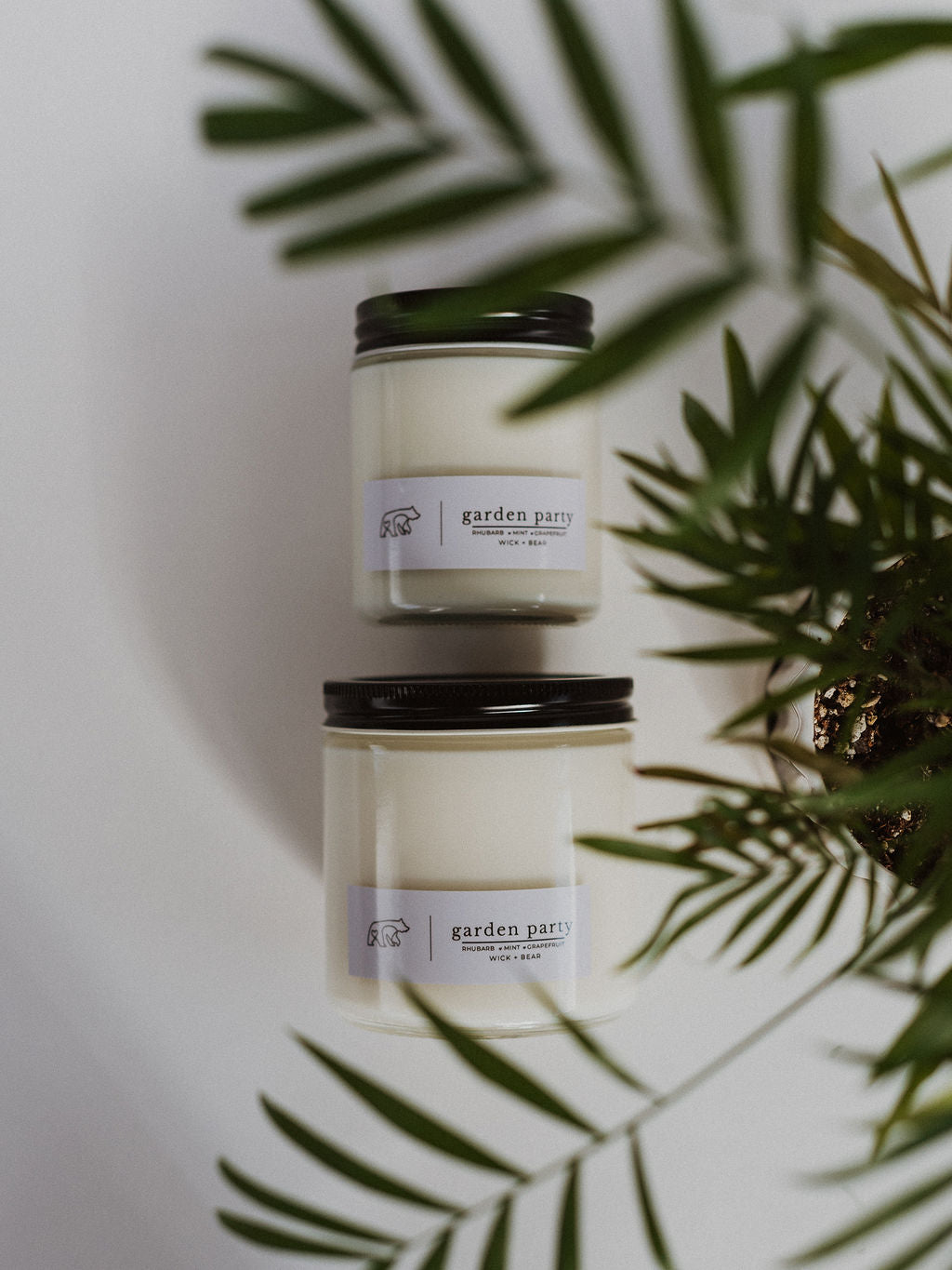 Two garden scented candles laying on their side displayed with a plant.